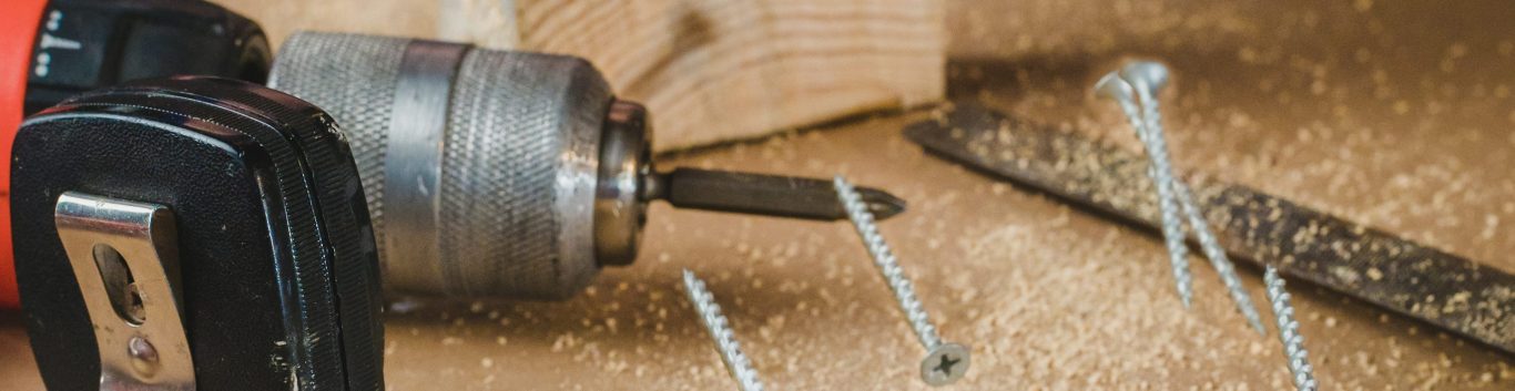 Boormachine met schroeven en hout op een werkbank met houtzaagsel. Boormachine met schroeven en hout op een werkbank met houtzaagsel.